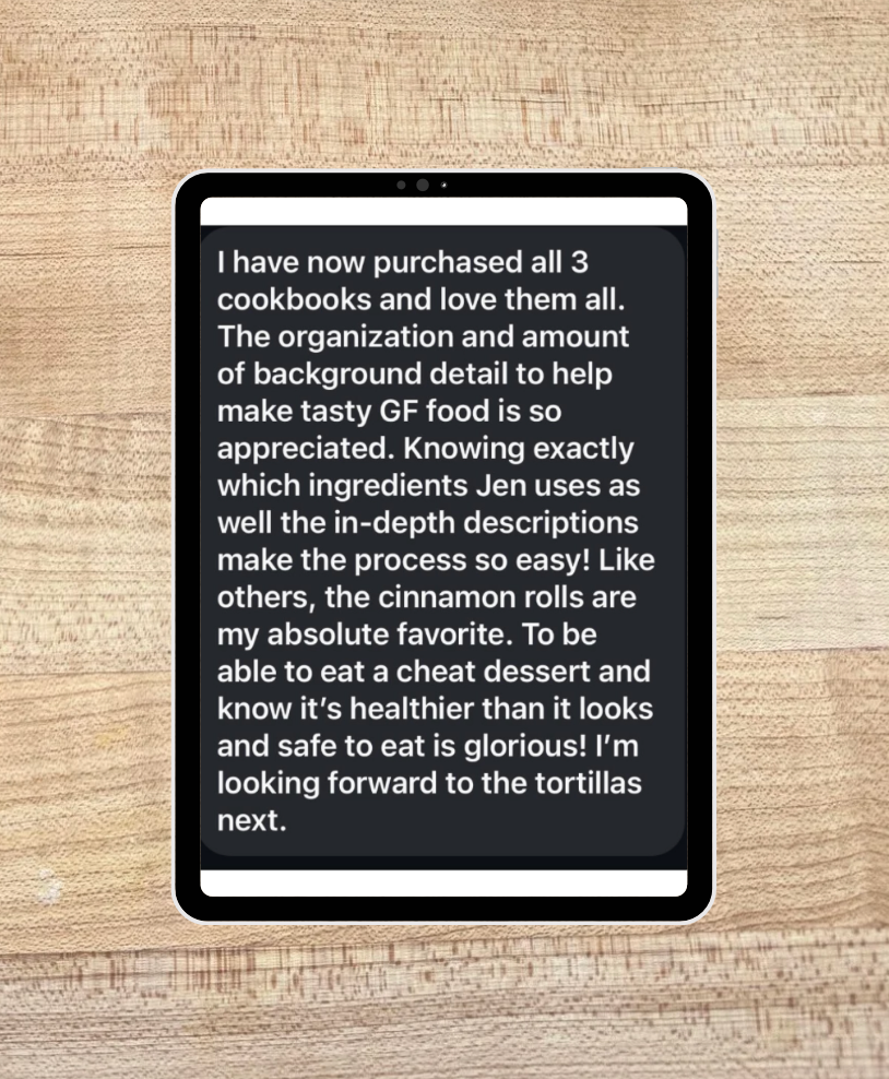 Text on a tablet screen displayed on a wooden surface with a positive review of 3 gluten free cookbooks 